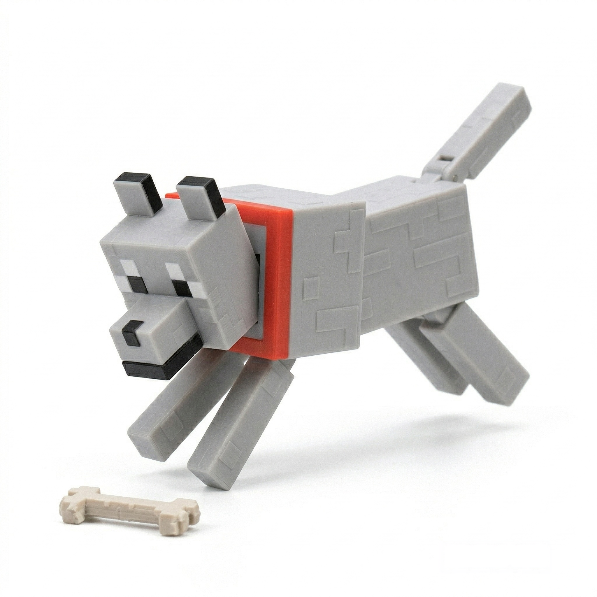 3D printed articulated voxel figure of a gray hound with a red collar, shown standing on a voxel grass biome and leaping toward a bone on a seamless white background